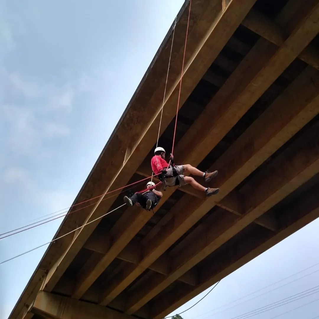 Profissional em rapel sob estrutura de ponte — trabalho em altura