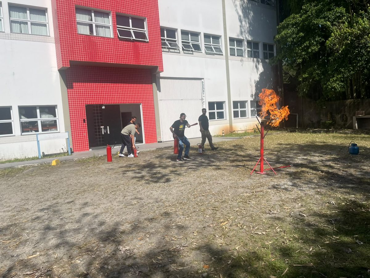 Brigada de incêndio com mangueira em torre industrial à noite